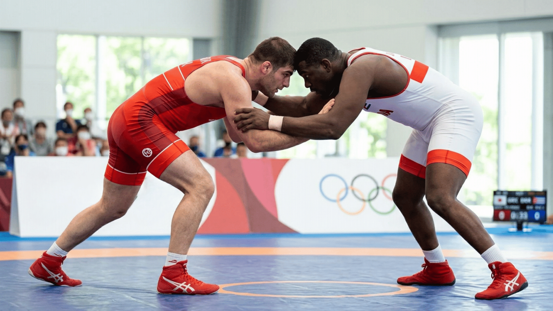 Two wrestlers grapple for control during a competitive freestyle match on an indoor mat