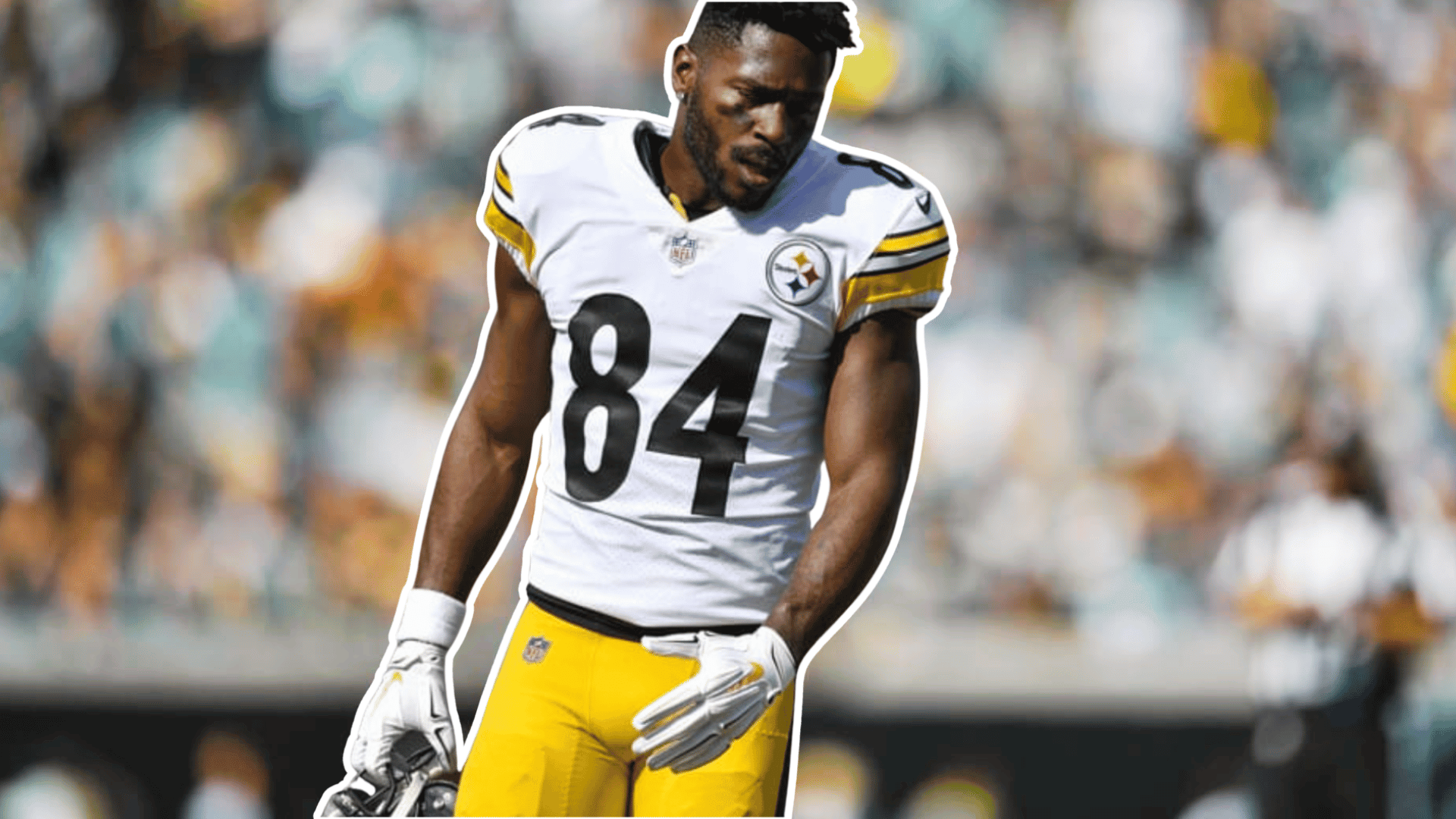 football player in a white jersey and yellow pants standing on the field with a blurred stadium crowd behind him