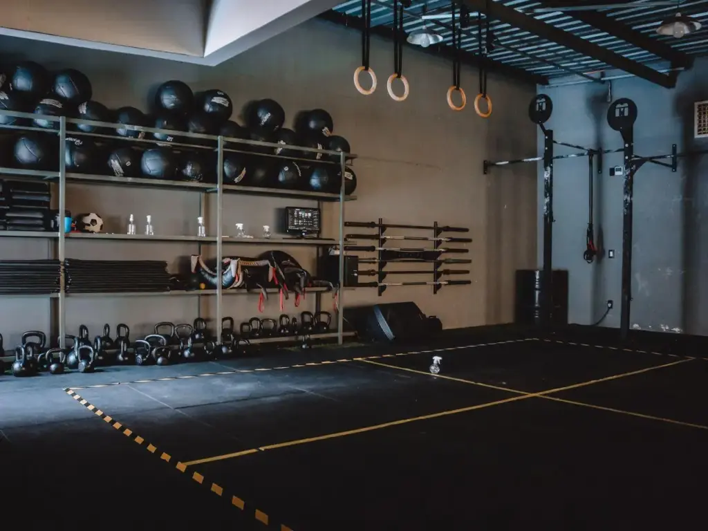 Crossfit gym interior with kettlebells, wall balls, and gymnastic rings under industrial lighting