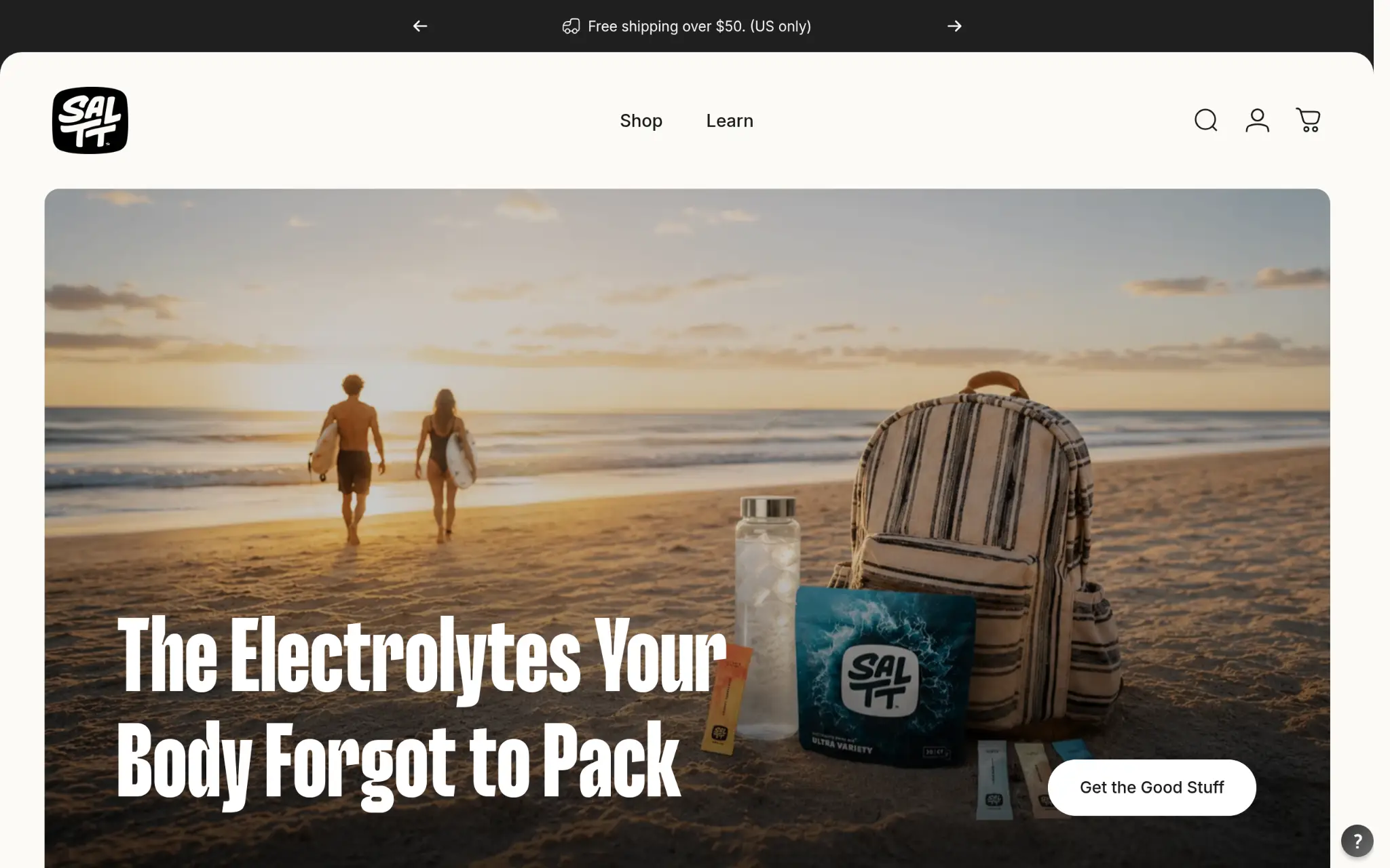 Striped backpack and electrolyte packets on sandy beach with ocean and sunset in background